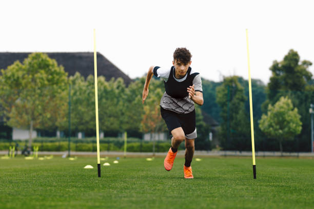 A young football player in a club's academy kit looking towards a brightly lit stadium pitch, symbolising ambition and the journey to the first team.